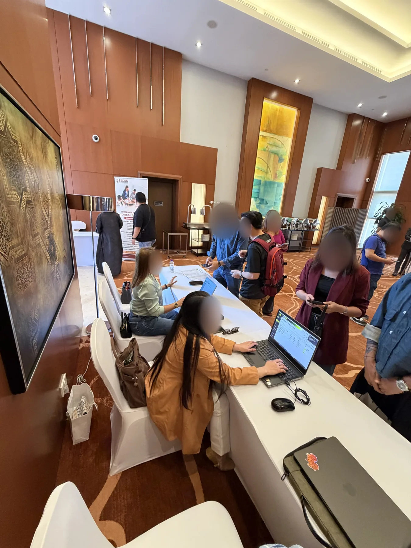 Registration desk with laptops while attendees scan in with their phones